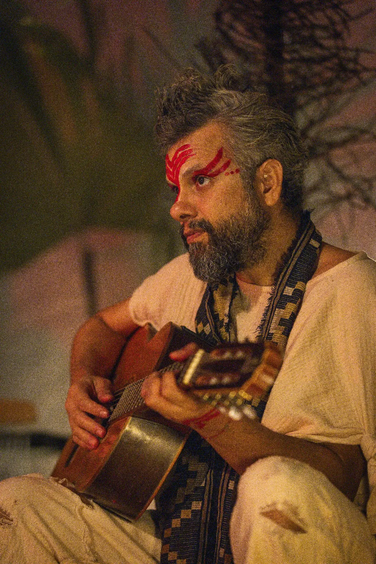 Artista entoando canção com instrumento ancestral